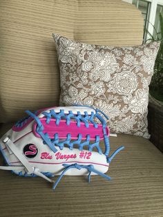 a pink and white baseball glove sitting on top of a couch next to a pillow