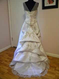 a wedding dress is displayed on a mannequin in front of a framed photograph