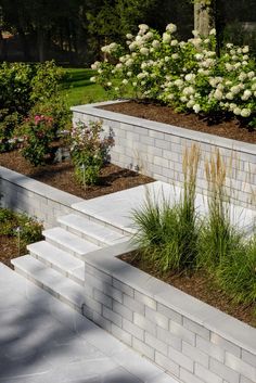 an outdoor garden with white brick walls and flowers in the foreground, grass growing on the other side