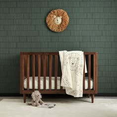 a baby crib with a teddy bear next to it in front of a green brick wall