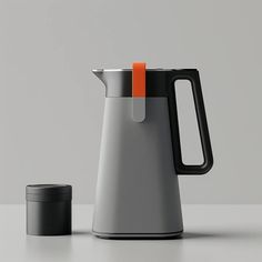 a coffee pot with an orange handle next to a black cup on a white table