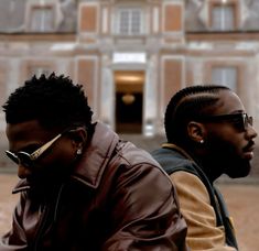 two men sitting on a bench in front of a building