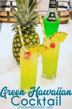 two glasses filled with pineapple cocktail on top of a table