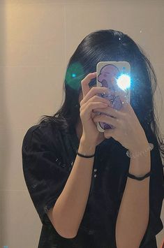 a woman taking a selfie in front of a mirror with her cell phone up to her face