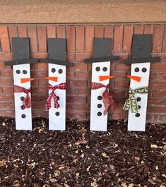 three snowmen are standing in front of a brick wall