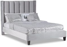 an upholstered bed with silver sheets and pillows is shown in front of a gray background