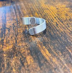 two silver cuff rings sitting on top of a wooden table