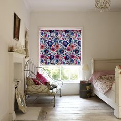 a bed room with a neatly made bed next to a window covered in floral curtains