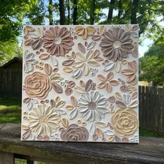 a card with flowers on it sitting on top of a wooden fence