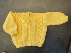 a child's yellow sweater laying on the floor