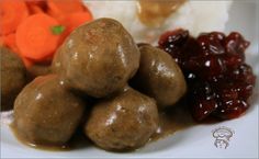 meatballs and cranberry sauce on a white plate with carrots in the background