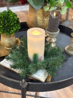 a lit candle sitting on top of a table next to some plants and candles in vases