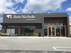 the front of a retail store with benches in front of it and blue skies above