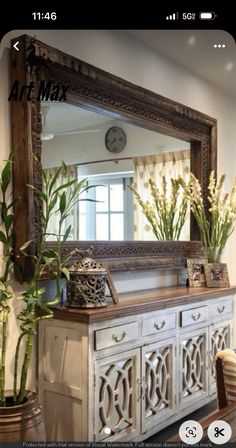 a mirror sitting on top of a wooden dresser next to a potted bamboo plant