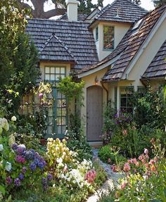 a house that is surrounded by flowers and trees