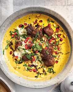 a bowl filled with meatballs and garnishes on top of a table