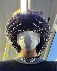 a person wearing a face mask with beads around their neck and hair in the back