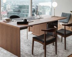 an office desk with two chairs and a laptop on it in front of a large window