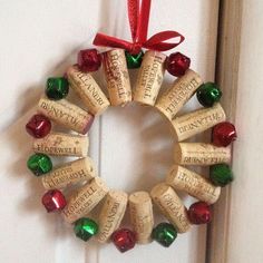 a wreath made out of wine corks hanging on a door with red and green ribbon