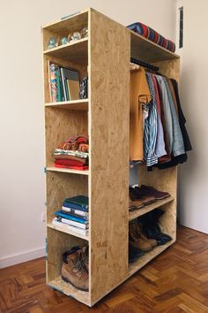 the closet is made out of plywood and has clothes on shelves, shoes, and other items in it