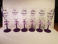 five wine glasses with purple bows and names on the bottom one is for bridesmaids