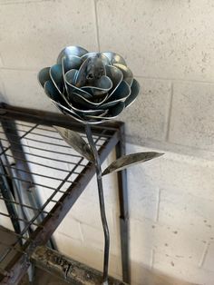 a metal rose sitting on top of a table next to a wire rack with scissors