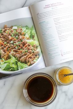 an open book with salad and sauces on the table