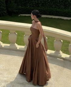 a woman in a brown dress standing on a balcony