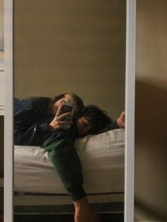 a man laying on top of a bed next to a woman taking a selfie