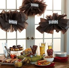 a table topped with plates and bowls filled with food next to a football themed window