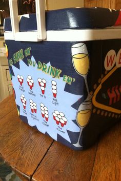 a cooler sitting on top of a wooden table filled with glasses of wine and drinks