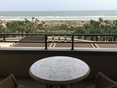 a table and chairs on a balcony overlooking the beach