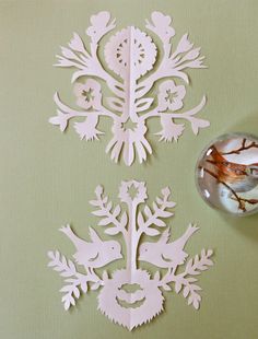 cut out paper snowflakes on a green background with a glass ornament