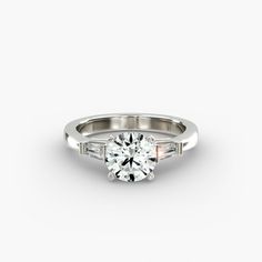 a white gold engagement ring with three baguets on the side and a round brilliant diamond in the center