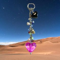 a heart shaped keychain hanging from a chain in the middle of a desert