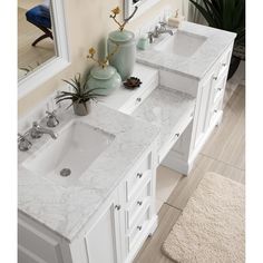 two sinks in a bathroom with mirrors and rugs on the floor next to them