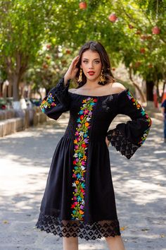 This Beautiful Dress boasts a Traditional Mexican floral design combined with a modern style dress. The embroidered bodice combined with the bell sleeves and lace make it fun and flirty. It's made out of fine Mexican cotton and has elastic around the top for an adjustable fit. This dress is handmade and embroidered by Mexican Artisans in Guanajuato, Mexico. Purchase the Men's Matching Guayabera here: https://www.etsy.com/es/listing/1184172577/guayabera-mexicana-bordado-floral-camisa?ref=listings Mexican Dresses Traditional Embroidery, Blue Mexican Dress, Spanish Style Dress Classy, Mexican Jacket Outfit, Mexican Black Dress, Mens Mexican Outfit, Black Mexican Dress, Elegant Mexican Dresses For Women, Modern Mexican Dress