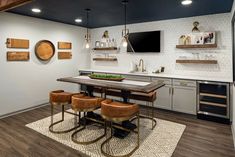 a kitchen with an island and bar stools next to the counter top in front of a flat screen tv