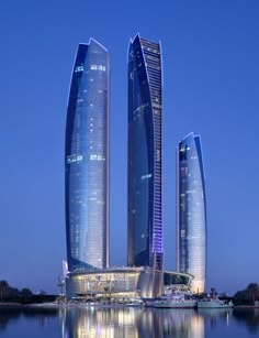 two tall skyscrapers sitting next to each other in the middle of a body of water