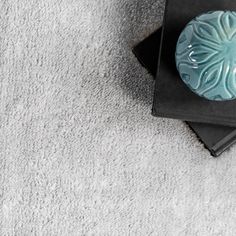 a blue vase sitting on top of a black table next to a white carpeted floor