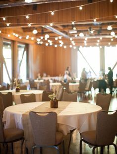 tables and chairs are set up in the middle of a room with lights hanging from the ceiling