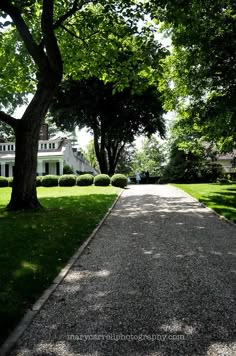 an empty driveway leading to a large white house