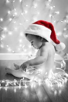 a black and white photo of a baby wearing a santa hat with lights around it