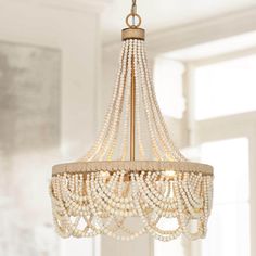 a chandelier with pearls hanging from it's sides in a room that has white walls and windows