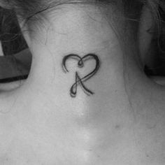 a woman's neck with a heart and scissors tattoo on the back of her neck