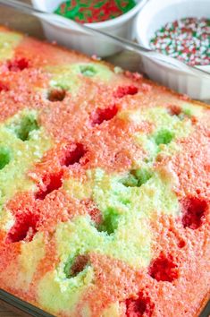 a cake in a pan on a table next to two bowls of sprinkles