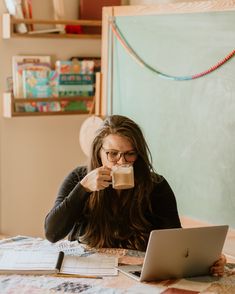 a woman drinking coffee while using her laptop