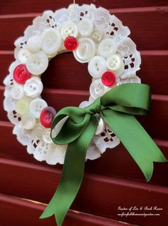 a white lace wreath with green ribbon and buttons