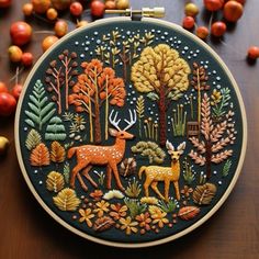 an embroidery project with deer and trees in the woods, surrounded by berries on a table