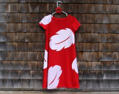 a red and white dress hanging on a wooden wall